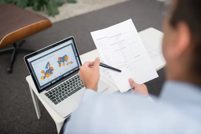Professional setting with businessman reviewing documents and data on a laptop in an office. How CRM products are reviewed here, and when scores are withheld